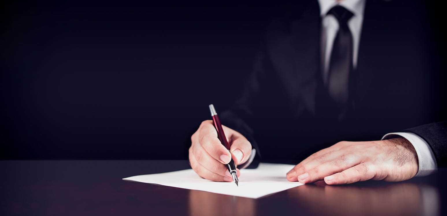 Man in black suit signing documents